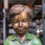 Statue d'un garçon lisant sur un banc