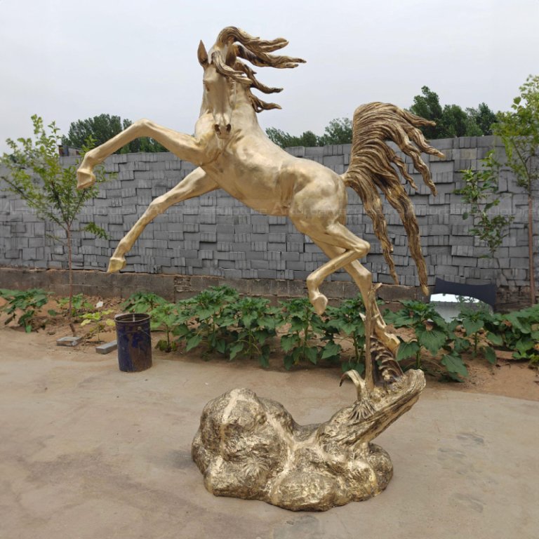 Golden Horse Sculpture mid-leap with raised front legs and flowing mane and tail