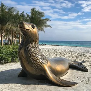 Bronze Sea Lion Statue lying on the beach with its head raised slightly