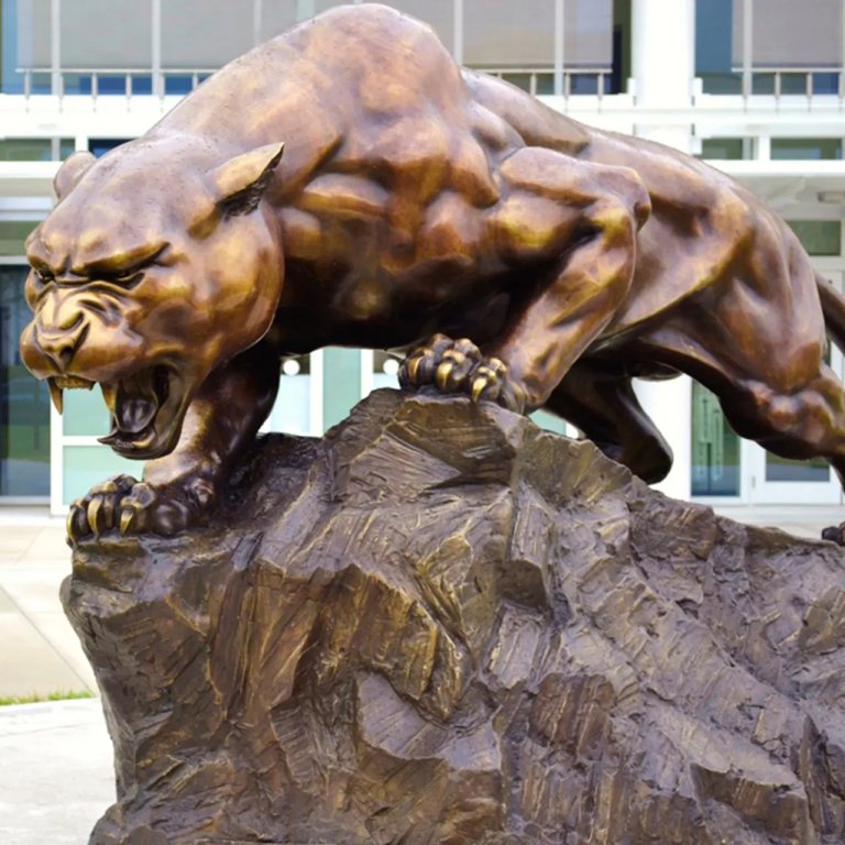 statue de panthère rugissante en bronze debout sur un rocher