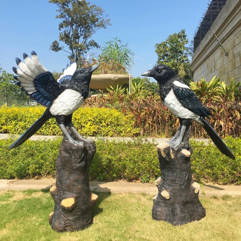 une paire de statues de jardin de pies sur branche, en fibre de verre