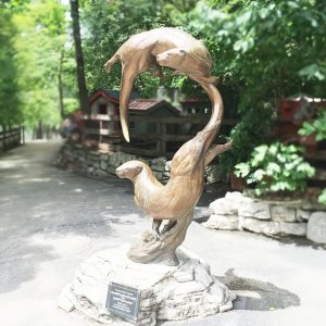 bronze Otter Garden Sculpture depicting two swimming otters, one above the other, both focused on the same point ahead