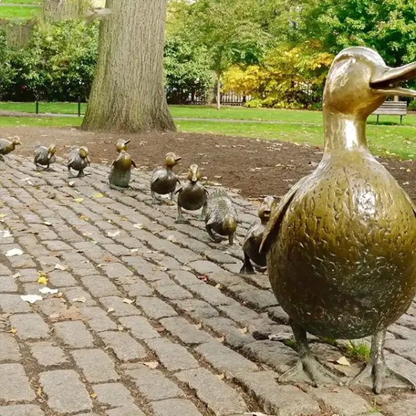 bronze Statue of Make Way for Ducklings showing mother duck with her ducklings walking on cobblestone