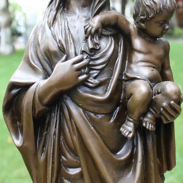 Detailed look at the sculpture of Mother Mary holding baby Jesus, showing the intricate folds of her robe and lifelike gestures