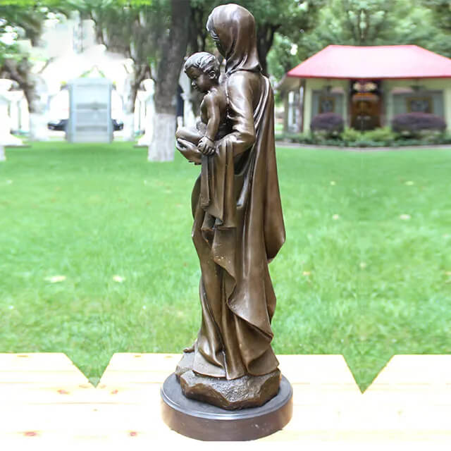 Side profile of the sculpture of Mother Mary gently holding baby Jesus