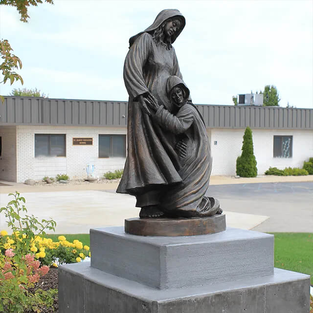 Side view of a bronze Visitation Statue featuring the Virgin Mary and Elizabeth in an emotional meeting