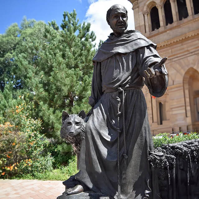 bronze St Francis and the Wolf Statue installed in front of the Cathedral Basilica of St. Francis of Assisi, with lifelike details of animals