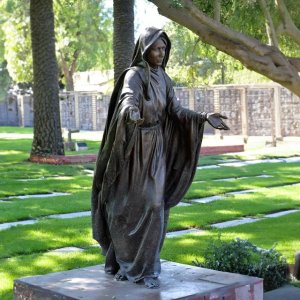 bronze Virgin Mary Lawn Statue with arms open in cemetery