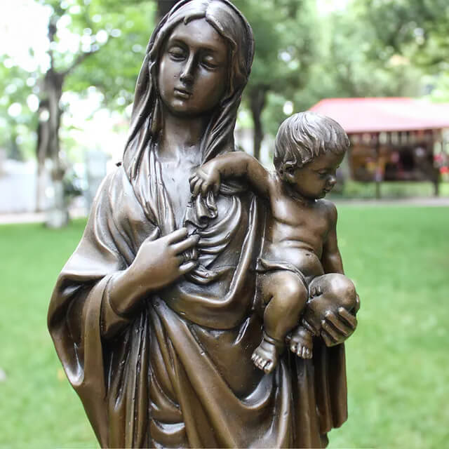 bronze sculpture of Mother Mary lovingly holding baby Jesus, highlighting their peaceful facial expressions and soft interaction