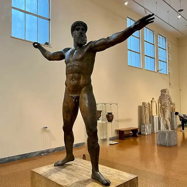 Artemision Bronze Sculpture inside the National Archaeological Museum in Athens, featuring the bearded figure poised to throw