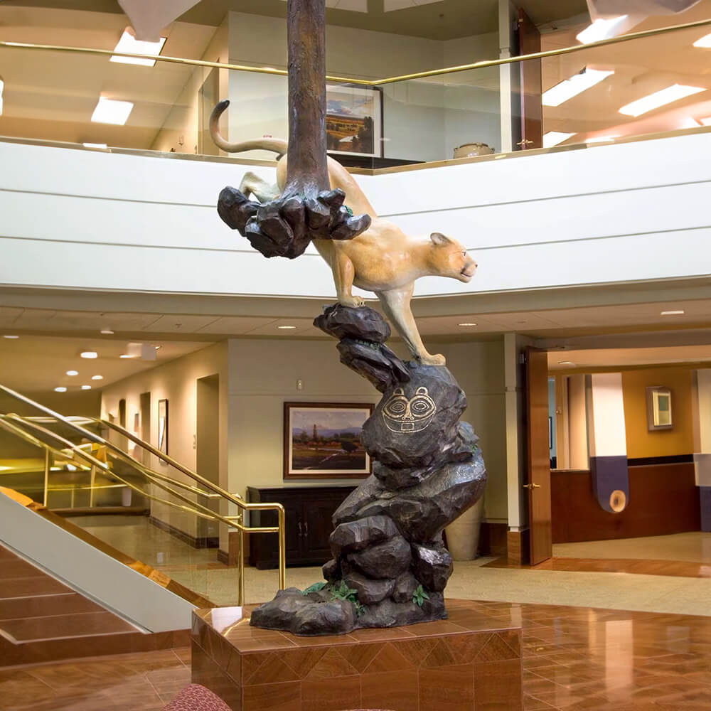 Large bronze Cougar Statue showing a mountain lion descending rocks and tree