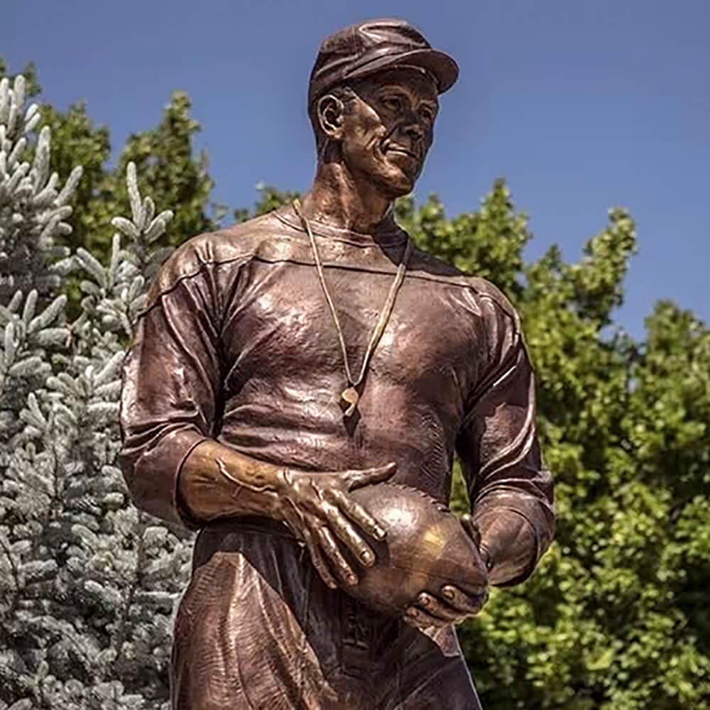 Bronze Coach Statue of Don Requa holding a football with serious expression