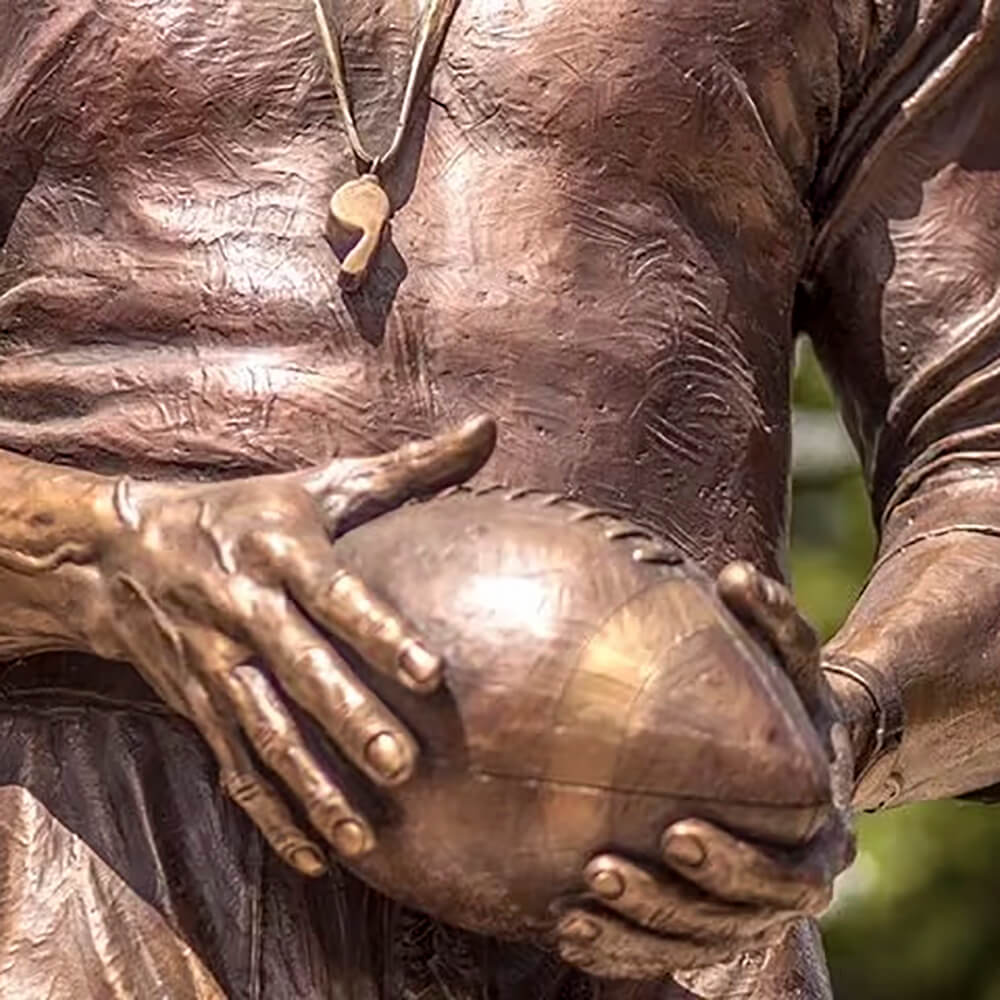 Close-up of football in hands of Don Requa bronze Coach Statue with whistle detail