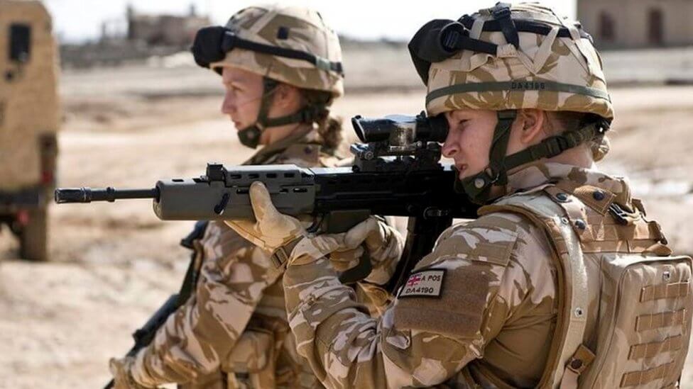Female soldiers in desert camouflage aiming weapons during live-fire military exercise