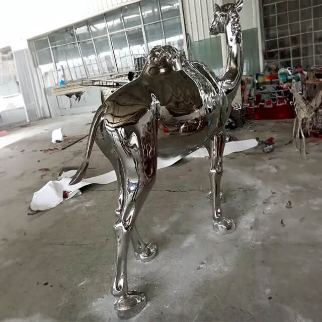 Polished stainless steel camel sculpture in outdoor yard
