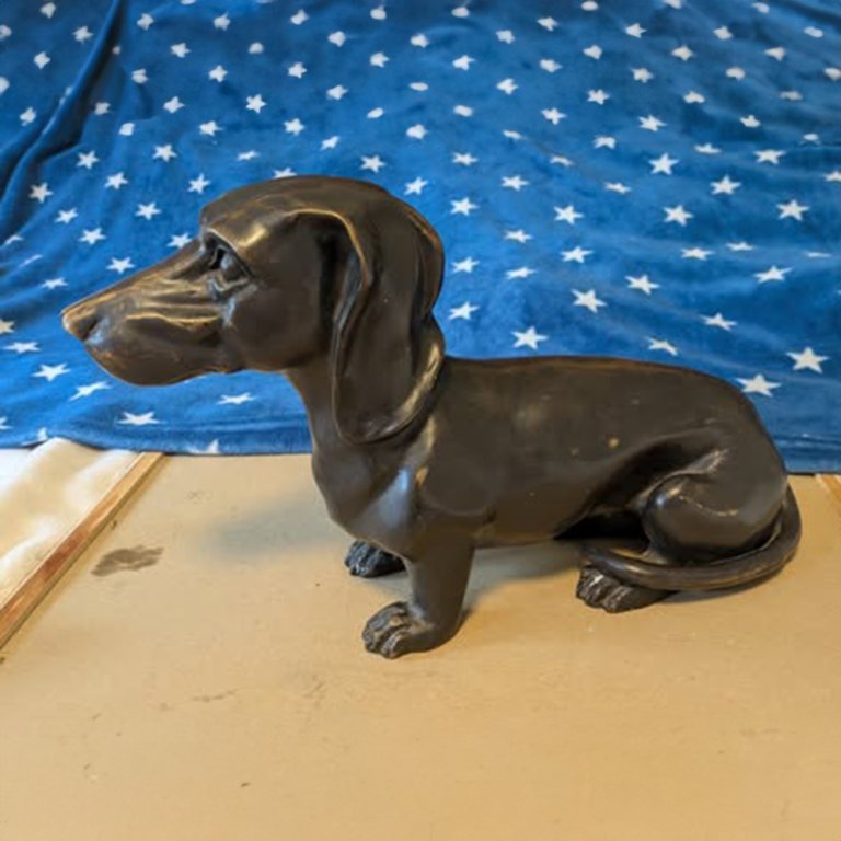 Estatua conmemorativa de bronce de un perro salchicha con postura sentada detallada y orejas largas