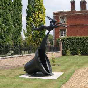 Bronze Running Hare Sculpture jumping over a tilted bell,