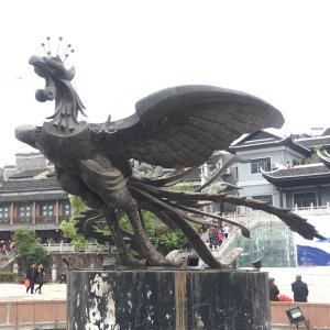 Grande statue en bronze du phénix, aux ailes déployées, posée sur un piédestal