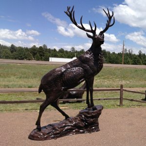 Large metal Elk Statue bronze artwork showing a majestic elk standing proudly on a rock with detailed antlers and muscular body