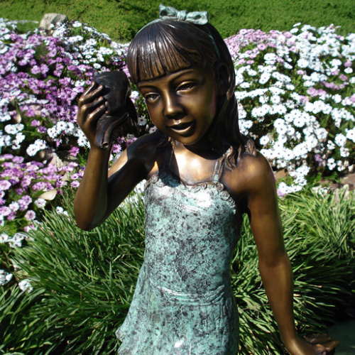 Détail rapproché de la statue en bronze de la jeune fille écoutant la coquille