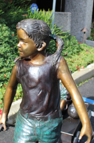 Statue frère et sœur : fille en bronze tirant une charrette