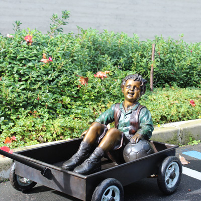 Statue frère et grande sœur : garçon en bronze dans une charrette